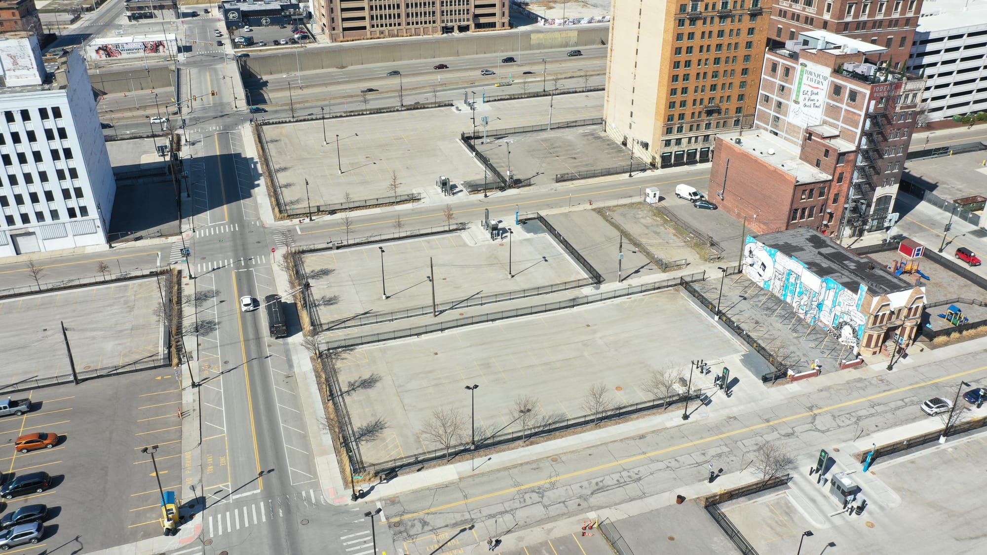 Aerial view of several blocks of surface parking lots with a few buildings and an interstate highway.