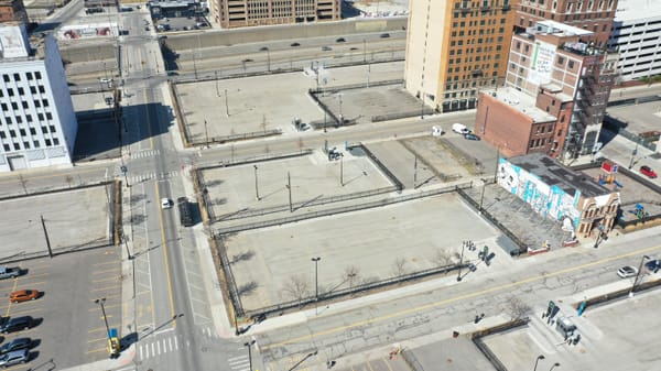 Aerial view of several blocks of surface parking lots with a few buildings and an interstate highway.